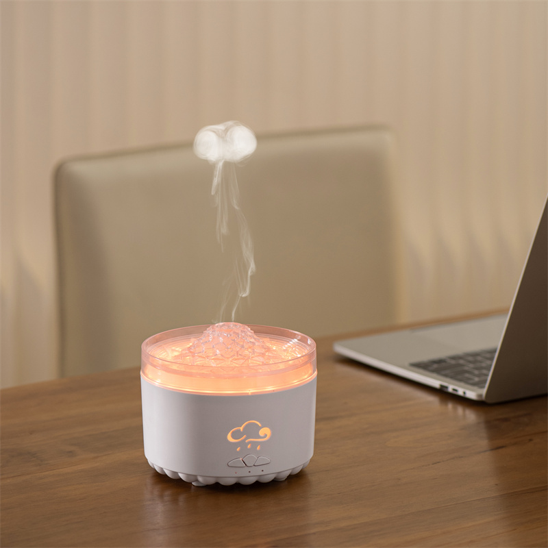 Yminigo V76B white volcano humidifier emitting a jellyfish smoke ring with warm orange lighting on a wooden desk